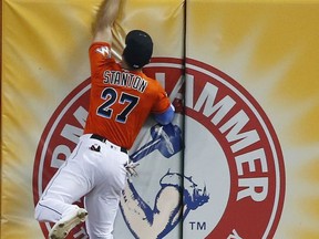 Miami Marlins right fielder Giancarlo Stanton loses his glove over the wall as he attempted to catch a triple hit by Los Angeles Dodgers' Chris Taylor during the fourth inning of a baseball game, Sunday, July 16, 2017, in Miami. The Dodgers defeated the Marlins 3-2. When Stanton made a running leap and stretched his left arm above the wall, his glove came off and fell to the other side. (AP Photo/Wilfredo Lee)