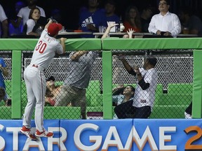 Philadelphia Phillies left fielder Cameron Perkins climbs the fence but is unable to catch a home run by Miami Marlins' Giancarlo Stanton during the fifth inning of a baseball game, Monday, July 17, 2017, in Miami. The Marlins defeated the Phillies 6-5 in 10 innings. (AP Photo/Wilfredo Lee)