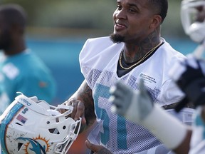 Miami Dolphins center Mike Pouncey puts on his helmet after stretching during an NFL football training camp, Thursday, July 27, 2017, at the Dolphins training facility in Davie, Fla. (AP Photo/Wilfredo Lee)