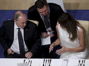 In this July 7, 2017 photo Russian President Vladimir Putin, left, and Melania Trump, wife of US-President Donald Trump, talk with a translator between them as they have dinner during the G20 summit in Hamburg, Germany.