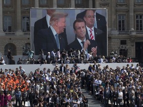 President Donald Trump, French President Emmanuel Macron and White House Chief of Staff Reince Priebus are seen on a large video screen during Bastille Day parade on the Champs Elysees avenue in Paris, Friday, July 14, 2017. (AP Photo/Carolyn Kaster)