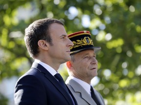 French President Emmanuel Macron, left, and Chief of the Defense Staff Gen. Pierre de Villiers, right, drive down the Champs Elysees avenue during Bastille Day parade in Paris, Friday, July 14, 2017.