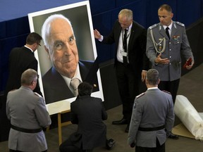 European Parliament employees set up a giant portrait of former German Chancellor Helmut Kohl before an European ceremony in Strasbourg, eastern France, Saturday Juny 1, 2017. Germany will later bid farewell to Kohl with a requiem Mass and military honors at the cathedral in Speyer, in his home region. (AP Photo/Michel Euler)