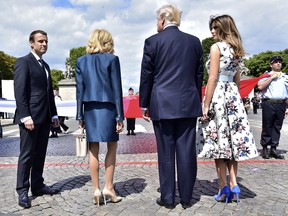 French President Emmanuel Macron, left, his wife Brigitte Macron, U.S President Donald Trump and First Lady Melania Trump, right, stand by a huge French flag after the Bastille Day military parade on the Champs Elysees avenue in Paris Friday, July 14, 2017.