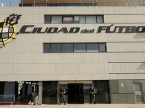 Spanish Civil Guard policemen stand guard outside the Spanish Football Federation headquarters during an anti-corruption operation in Las Rozas, outside Madrid, Tuesday, July 18, 2017. Spanish Football Federation President Angel Maria Villar was arrested Tuesday along with his son and two more federation executives as part of an anti-corruption probe. Words on the facade on the building read in Spanish: "City of Soccer." (AP Photo/Francisco Seco)