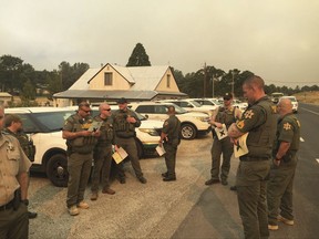 Merced and Mariposa County Sheriff's Office members attend a briefing during a wildfire in Mariposa County, Calif., Tuesday, July 18, 2017. Tall grass from a deluge of winter rains is fueling wildfires throughout the Western U.S., damaging more than a dozen homes in Nevada and threatening hundreds more structures in California. The California Department of Forestry and Fire Protection on Tuesday ordered evacuations for some residents living southwest of Yosemite National Park. (Merced County Sheriff's Office via AP)