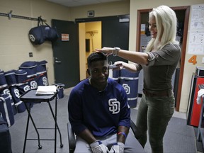 In this photo taken Thursday, July 20, 2017, hairstylist Lara Albertsen uses a foil trimmer on San Diego Padres' Jose Pirela before the team's baseball game against the San Francisco Giants in San Francisco. The hairstylist based in the East Bay suburb of Danville shows up for the first game of a series to snip for any interested players or coaches and her room has been named "Big Mac Salon" after former slugger turned Padres bench coach Mark McGwire paid a visit for a haircut July 20 before the series opener against the Giants. (AP Photo/Eric Risberg)