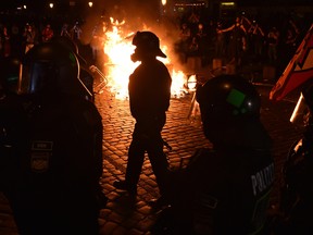 Police officers walk in front of a fire started by protesters at the "Welcome to Hell" rally against the G20 summit in Hamburg, northern Germany on July 6, 2017.
