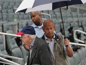 Former President Jimmy Carter leaves his seat as rain begins to fall before a baseball game between the Chicago Cubs and the Atlanta Braves Tuesday, July 18, 2017, in Atlanta. (AP Photo/John Bazemore)