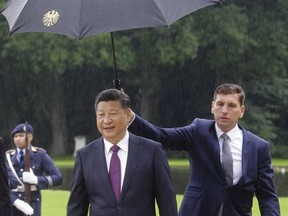 The President of the People's Republic of China Xi Jinping, right, walks through the rain during the welcoming ceremony at Bellevue Palace in Berlin, Wednesday, July 5, 2017. (AP Photo/Markus Schreiber)
