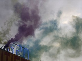 A demonstrator lights smoke markers on top of the Rote Flora squat during a protest against the G-20 summit in Hamburg, northern Germany, Wednesday, July 5, 2017. The leaders of the group of 20 meet July 7 and 8. (AP Photo/Matthias Schrader)