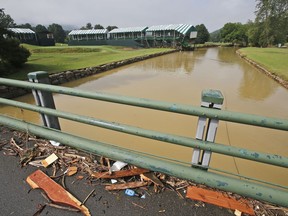 FILE - In this June 28, 2016, file photo, debris from floodwaters litters a pedestrian bridge above Howard Creek along the 18th hole of the Old White Course at the Greenbrier Resort in White Sulphur Springs, W. Va.  Last year's Greenbrier Classic golf tournament was canceled after torrential downpours triggered flooding that killed 23 people statewide, including 15 in Greenbrier County, and caused extensive damage to The Greenbrier resort. (AP Photo/Steve Helber, File)