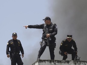 Police officers work to contain a prison riot, from the roof of one of the buildings of the Juvenile Correctional Center Gaviotas in Guatemala City, Monday, July 3, 2017. The riot began when two inmates were found hanging in an apparent suicide, according to authorities. Apart from the two dead, 10 other inmates are reported to have escaped from the center. (AP Photo/Moises Castillo)