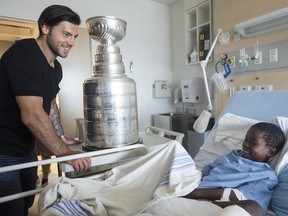 Kris Letang shows off the Stanley Cup to Owen Yekpe during a visit to Sainte Justine hospital for sick children in Montreal on July 23.