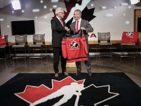 Hockey Canada's president and CEO Tom Renney, left, congratulates Team Canada's 2017-18 head coach, Willie Desjardins, at a news conference in Calgary on July 25.