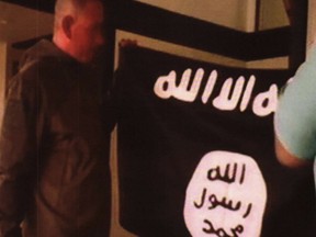 In this image taken from FBI video and provided by the U.S. Attorney's Office in Hawaii on Thursday, July 13, 2017, Army Sgt. 1st Class Ikaika Kang holds an Islamic State group flag after allegedly pledging allegiance to the group at a house in Honolulu on July 8. The active duty soldier based in Hawaii helped purchase a drone for the Islamic State group to use against American forces and said he wanted to use his rifle to "kill a bunch of people," according to an FBI affidavit. A detention hearing is set for Kang on Thursday. (FBI/U.S Attorney's Office, District of Hawaii via AP)