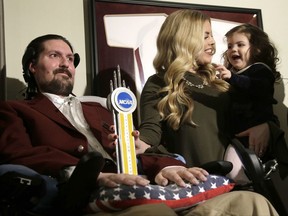 FILE - In this Dec. 13, 2016, file photo, former Boston College baseball captain Pete Frates, left, appears with his wife Julie, center, and two-year-old daughter Lucy, right, moments after he was presented with the 2017 NCAA Inspiration Award, at their home in Beverly, Mass. Pete Frates, the Massachusetts man who inspired people around the world to dump buckets of ice water over their heads to raise millions of dollars for Lou Gehrig's disease research is back in the hospital. A Facebook post from the family of Pete Frates asked for prayers Sunday, July 2, 2017, and said he is at Massachusetts General Hospital "and battling this beast ALS like a Superhero." (AP Photo/Steven Senne, File)