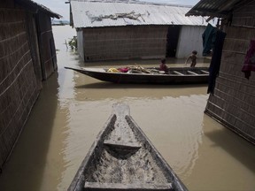 An Indian child sits in a boat as another stands near their house partially submerged in flood waters in Burgaon, 80 kilometers (50 miles) east of Gauhati, Assam state, India, Wednesday, July 5, 2017. Heavy rains since the start of India's monsoon season have triggered floods and landslides in parts of the remote northeastern region, causing at least 20 deaths, authorities said Wednesday. (AP Photo/Anupam Nath)