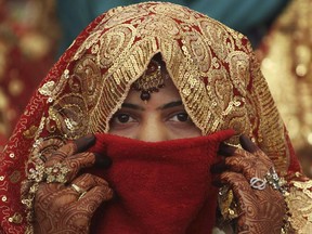 An Indian bride covers her face during the Muslim community mass marriage in Ahmadabad, India, Friday, Feb. 22, 2013. A total of 151 Muslim couples tied the knot at the mass marriage. Mass marriages in India are organized by social organizations primarily to help the economically backward families who cannot afford the high ceremony costs as well as the customary dowry and expensive gifts that are still prevalent in many communities. (AP Photo/Ajit Solanki) ORG XMIT: DEL181