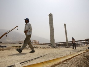 FILE - In this July 19, 2010 file photo, Iranian workers walk in a construction site which is part of South Pars gas field, on the northern coast of Persian Gulf, Iran.  Iran on Monday, July 3, 2017 signed a $5 billion agreement with France's Total SA and a Chinese oil company to develop its massive offshore natural gas field, the first such deal with foreign companies since the landmark 2015 nuclear deal with world powers. (AP Photo/Vahid Salemi, File)