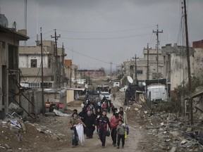 FILE - In this March 13, 2017 file photo, Iraqi civilians flee their homes during fighting between Iraqi security forces and Islamic State militants, on the western side of Mosul, Iraq. 3,351,132 _ The number of Iraqis across the country who remained displaced by violence in the fight against IS as of June 30, according to the U.N. migration agency. As Iraqi forces have retaken territory from the militants, more than 1,952,868 people have been able to return home. Of those still displaced, the vast majority are from Nineveh province, where Mosul is located. Some 700,000 are sheltering in camps, while the rest are living with extended family or in rented housing. (AP Photo/Felipe Dana, File)