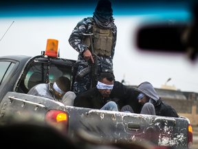 Iraqi Christian militia fighters drive a pickup truck in Qaraqosh (also known as Hamdaniya), transporting four prisoners, allegedly members of the Islamic State group.