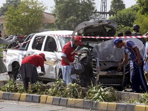 Pakistani security officers and volunteers collect evidence at the site of a bombing in Peshawar, Pakistan, Monday, July 17, 2017.  A suicide bomber hit a vehicle carrying Pakistani paramilitary force members on Monday, killing soldiers, including an officer, and wounding seven, a police official said. The Taliban quickly claimed responsibility for the attack. (AP Photo/Muhammad Sajjad)