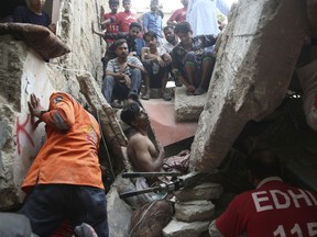 Pakistani volunteers try to rescue a trapped resident in Karachi, Pakistan, Tuesday, July 18, 2017. A dilapidated, three-story building in a poorer neighborhood of Pakistan's sprawling port city of Karachi collapsed as the residents slept. (AP Photo/Shakil Adil)