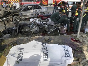 Pakistani rescue workers remove a body from the site of bombing in the eastern city of Lahore, Pakistan, Monday, July 24, 2017. Pakistani officials said that the car bomb killed over 10 people and wounded more than 20 others at a vegetable market in Kot Lakhpat. (AP Photo/K.M. Chaudary)