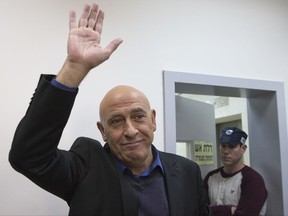 FILE -- In this Dec. 26, 2016 file photo, then Arab Israeli lawmaker Basel Ghattas waves as he enters a magistrate courtroom in Rishon Lezion. Ghattas entered prison Sunday, July 2, 2017 saying he is going to prison with "pride" as he begins a two-year sentence. Earlier this year an Israeli court accepted a plea bargain in which Ghattas resigned from parliament and admitted to smuggling phones and SIM cards to Palestinian prisoners held by Israel. (AP Photo/Ariel Schalit, File)