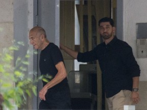 Former Israeli Prime Minister Ehud Olmert, left, exits prison after his sentence, in Ramle, Israel, Sunday, July 2, 2017. The parole board of Israel's Prison Service has granted Olmert early release from prison. Prison Service spokesman Assaf Librati says the board granted Olmert's request to reduce a third of his 27-month incarceration sentence. (AP Photo/Ariel Schalit)