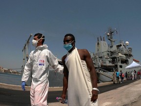 An Italian paramedic helps a migrant during the disembark of 402 migrants from the Britain Royal Navy's ship Echo in the harbor of Brindisi, Italy, Friday June 30, 2017. (Max Frigione /ANSA via AP)