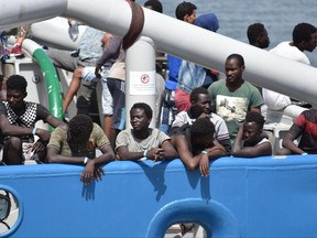 Migrants stand on the deck of the Swedish Navy ship Bkv 002, as they wait to disembark in the Sicilian harbor of Catania, Italy, Saturday, July 1, 2017. The Swedish ship carried 650 migrants, rescued in various operations in the Mediterranean Sea, and the dead bodies of seven men and two women, authorities said. (Orietta Scardino/ANSA via AP)