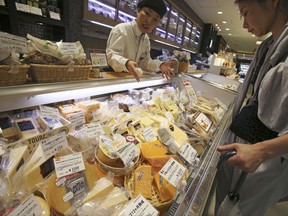 In this Saturday, July 1, 2017, photo, a customer looks at various types of imported cheese sold at a department store in Tokyo. Japan's foreign minister is preparing to head to Brussels to seek a breakthrough in talks on a free trade agreement with the European Union. Foreign Minister Fumio Kishida said over the weekend that he was hopeful the two sides would resolve remaining differences, mainly over trade in cheese and autos, before Friday's summit of the Group of 20 industrial nations. (AP Photo/Koji Sasahara)