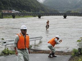 Workers inspect a swollen river after heavy rain hit the area in Miyoshi, Hiroshima prefecture, western Japan, Wednesday, July 5, 2017. Heavy rain following the recent typhoon has left a man found dead and flooded many houses in southwestern Japan. (Shohei Miyano/Kyodo News via AP