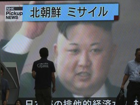 In this Tuesday, July 4, 2017, photo, people walk in front of an image of North Korean leader Kim Jong Un shown on a large screen as a TV news reports the North Korea's missile test which landed in the waters of Japan's economic zone, in Tokyo.