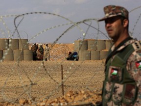 In this Feb. 14, 2017 file photo, a Jordanian soldier stands guard at the northeastern border with Syria, close to the informal Rukban camp for displaced Syrians. Desperate to help Syrians stuck on Jordan's sealed border, U.N. agencies reluctantly agreed late last year to hand much of the control over aid distribution to Jordan's military, a Jordanian contractor and a Syrian militia. Since then, the system has broken down repeatedly and only sporadic aid shipments have reached the two remote desert camps on the border. (AP Photo/Raad Adayleh, File)