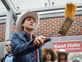 Prime Minister Justin Trudeau, centre, flips flapjacks at a Stampede breakfast in Calgary, Alta., Saturday, July 16, 2016.THE CANADIAN PRESS/Jeff McIntosh ORG XMIT: JMC105