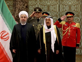 FILE - In this Feb. 15, 2017 file photo released by official website of the office of the Iranian Presidency, President Hassan Rouhani, left, is welcomed by Kuwaiti Emir Sheikh Sabah Al Ahmed Al Sabah, center, at the Kuwait International Airport, in Farwaniya, Kuwait, 15.5 kilometers (9.6 mi) south of Kuwait City. The official Kuwait News Agency announced Thursday , July 20, 2017, that it is shutting the Iranian cultural mission and related offices in the Gulf Arab state and reducing the number of Iranian diplomats stationed in the country. (Iranian Presidency Office via AP, File)