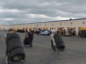 Race teams rush to get cars and equipment put away ahead of an incoming thunderstorm, at Kentucky Speedway on Friday, July 7, 2017, in Sparta, Ky. The Xfinity race scheduled for Friday night was pushed back to Saturday. (AP Photo/Timothy D. Easley)