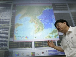 FILE - In this Aug. 28, 2006, file photo, Heon-Cheol Chi, director of the Korea Earthquake Research Center explains about the concerns of a possible nuclear test growing in North Korea in front of a real time event map at the Korea Institute of Geoscience and Mineral Resources in Daejon, some 165 kilometers (100 miles) south of Seoul, South Korea. Heon-Cheol Chi was convicted Monday, July 17, 2017, of taking more than $1 million in bribes from companies in Pasadena, Calif., and England and funneling proceeds through U.S. banks. (AP Photo/Lee Jin-man, File)