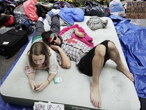 FILE - In this Sept. 26, 2011, file photo, Amber Oestreich, left, and Robert Grodt, who are part of the protest movement Occupy Wall Street, rest on a mattress in New York's Zuccotti Park. People's Protection Units, also known by their Kurdish initials as the YPG, a U.S.-backed Syrian Kurdish militia, said Tuesday, July 11, 2017, that two American volunteers were killed fighting the Islamic State group in northern Syria last week. (AP Photo/Mark Lennihan, File)