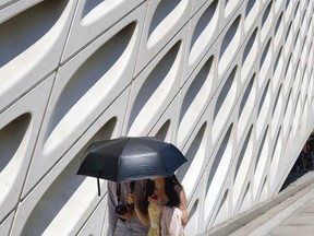 Tourists walking past The Broad Museum while they shade themselves from the afternoon sun in downtown Los Angeles on Friday, July 7, 2017. Southern California faces more blistering heat as firefighters around the state work to corral wildfires. The National Weather Service says high temperatures between 100 and 110 degrees will be common away from the coast Friday and Saturday while some coastal sections could see highs into the 90s. (AP Photo/Richard Vogel)