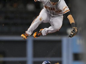 San Francisco Giants second baseman Joe Panik jumps over Los Angeles Dodgers' Austin Barnes after missing the throw from home as Barnes advances to second on a wild pitch during the fifth inning of a baseball game, Friday, July 28, 2017, in Los Angeles. Barnes advanced to third on a throwing error by catcher Nick Hundley on the play. (AP Photo/Mark J. Terrill)