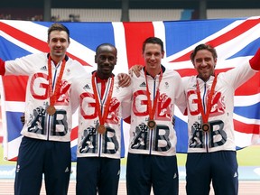 Great Britain's 4x400 metre relay team from the 2008 Olympics, from left, Martyn Rooney, Michael Bingham, Robert Tobin and Andrew Steele celebrate after upgrading to third place and receiving a bronze medal during the London Anniversary Games at London Stadium, London, Sunday July 9, 2017. (Paul Harding/PA via AP)