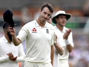 England's Toby Roland-Jones holds up his hat to applause as he leaves the pitch after taking the wicket of South Africa's Temba Bavuma on the third day of the third test match between England and South Africa at The Oval cricket ground in London, Saturday, July 29, 2017. (AP Photo/Kirsty Wigglesworth)