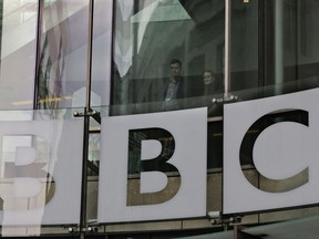 FILE- In this Thursday, March 28, 2013 file photo, people watch from inside BBC's New Broadcasting House, as BBC journalists and technical staff on strike, not seen, form a picket line outside the building in central London. The publicly funded BBC has published the names and salaries of its highest-earning actors and presenters, revealing that its best-paid star, radio host Chris Evans, earns more than 2.2 million pounds ($2.9 million) a year. (AP Photo/Lefteris Pitarakis, File)