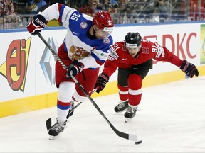 FILE - This is a Friday, May 9, 2014  file photo of Russia's Danis Zaripov, left, as he is  challenged by Switzerland's Robin Grossmann during the Group B preliminary round match between Switzerland and Russia at the Ice Hockey World Championship in Minsk, Belarus. Danis Zaripov, who played for Russia at the 2010 Olympics, is among three Kontinental Hockey League players banned for doping. The league said Tuesday July 25, 2017 that  Zaripov tested positive during the 2016-17 season for unnamed substances including a stimulant and a banned diuretic or masking agent. (AP Photo/Darko Bandic/File)