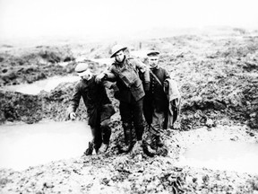 FILE - In this file photo dated 1917, wounded Canadian and German World War One soldiers help one another through the mud during the Battle of Passchendaele, in Passchendaele, Belgium.  Monday July 31, 2017, marks the centennial of the start of the World War I battle of Passchendaele which barely moved the frontline and thus became a metaphor for the folly of warfare. (AP Photo/FILE)