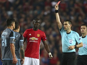 FILE - This is a Thursday, May 11, 2017 file photo of referee Ovidiu Hategan, second right, as he shows the red card and sends off both Manchester United's Eric Bailly, centre,  and Celta's Facundo Roncaglia, left, during the Europa League semifinal second leg soccer match between Manchester United and Celta Vigo at Old Trafford in Manchester, England.  UEFA said Monday July 24, 2017 that Manchester United defender Eric Bailly is suspended from the Super Cup game against Real Madrid and a Champions League group-stage game. UEFA's disciplinary panel imposed a three-match ban for violent conduct after Bailly was sent off late in Man United's Europa League semifinal, second-leg game against Celta Vigo in May. (AP Photo/Dave Thompson/File)